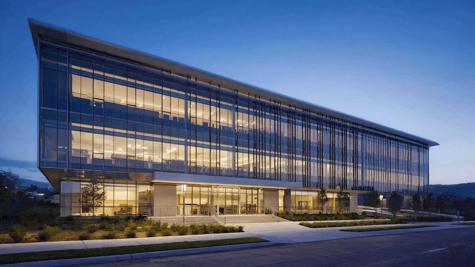 Modern glass office building exterior at dusk with illuminated interior lights and contemporary corporate architecture