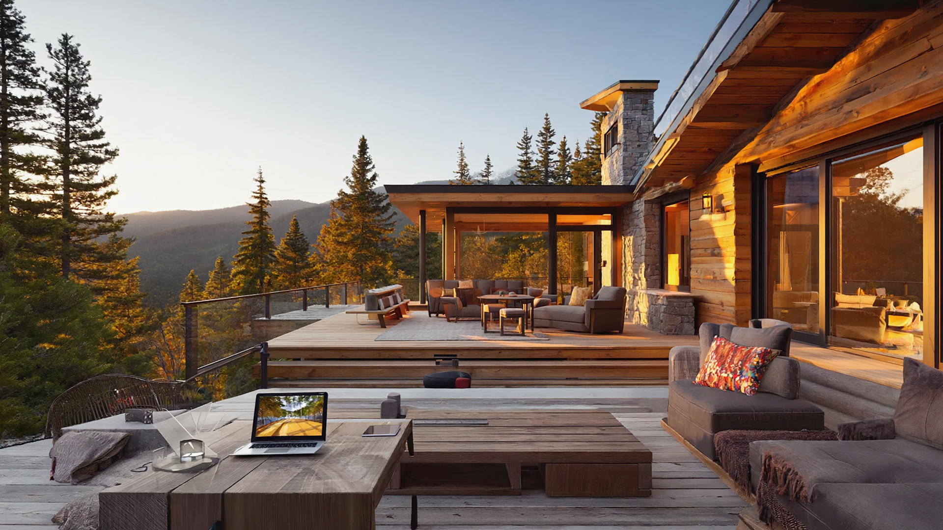 Luxury mountain cabin with spacious wooden deck, outdoor lounge seating, and panoramic forest sunset views